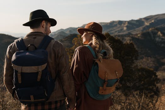 A couple enjoys a mountain hike, wearing hats and backpacks, embracing nature's beauty.