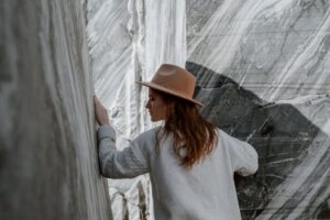 Woman in fedora and sweater exploring rocky marble canyon outdoors.